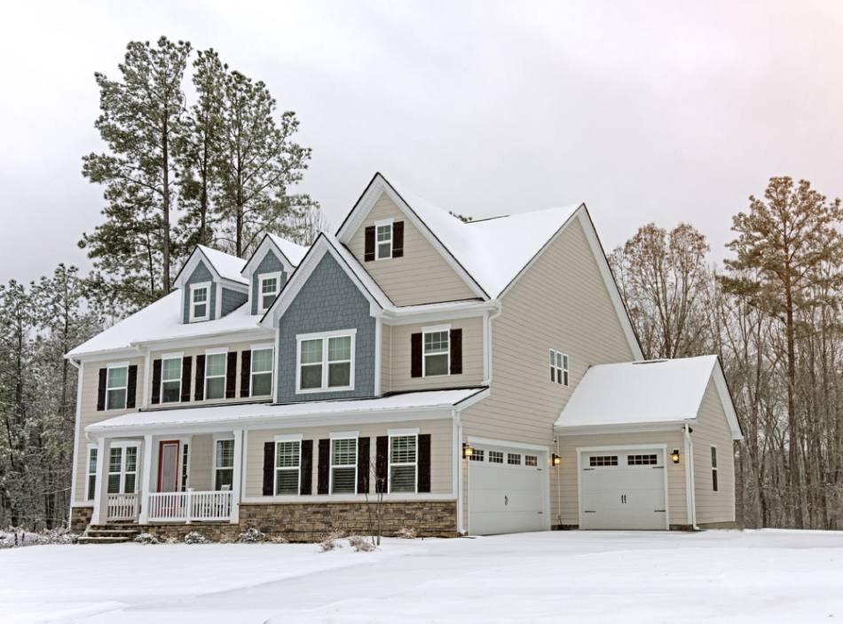 Large home with off-white siding covered with snow
