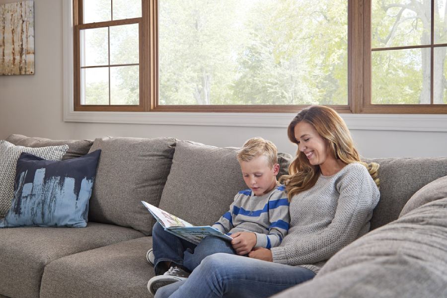 Mother and son reading book in front of bay window
