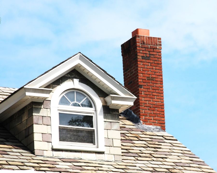 Close up chimney on the roof featuring geometric shaped window.